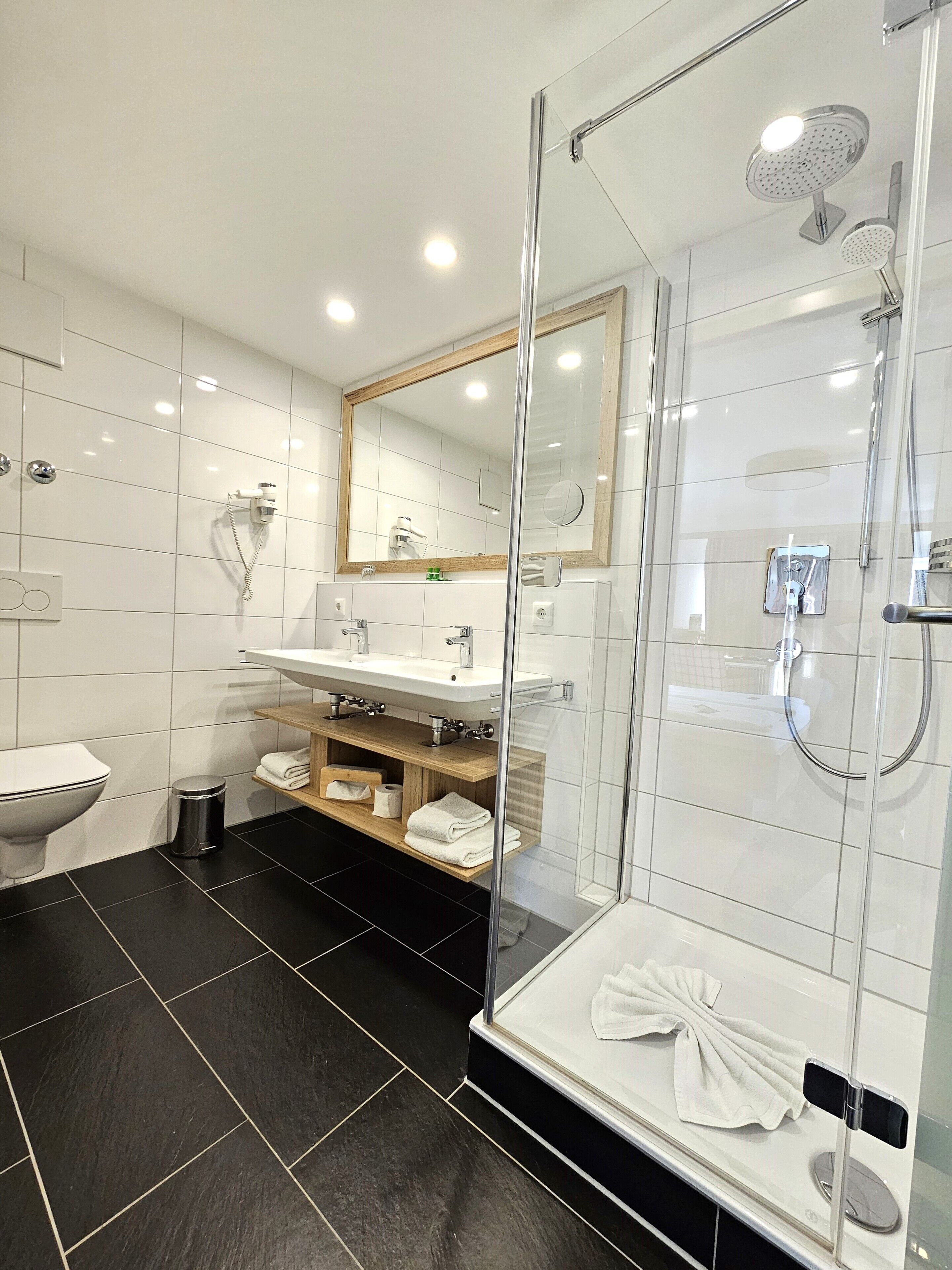 A modern bathroom with a glass-enclosed shower, a white sink, and a mirror above the sink.