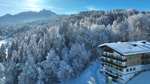 A hotel with a view of snow-covered trees and mountains. - Naturhotel Waldesruhe (Oberstdorf)