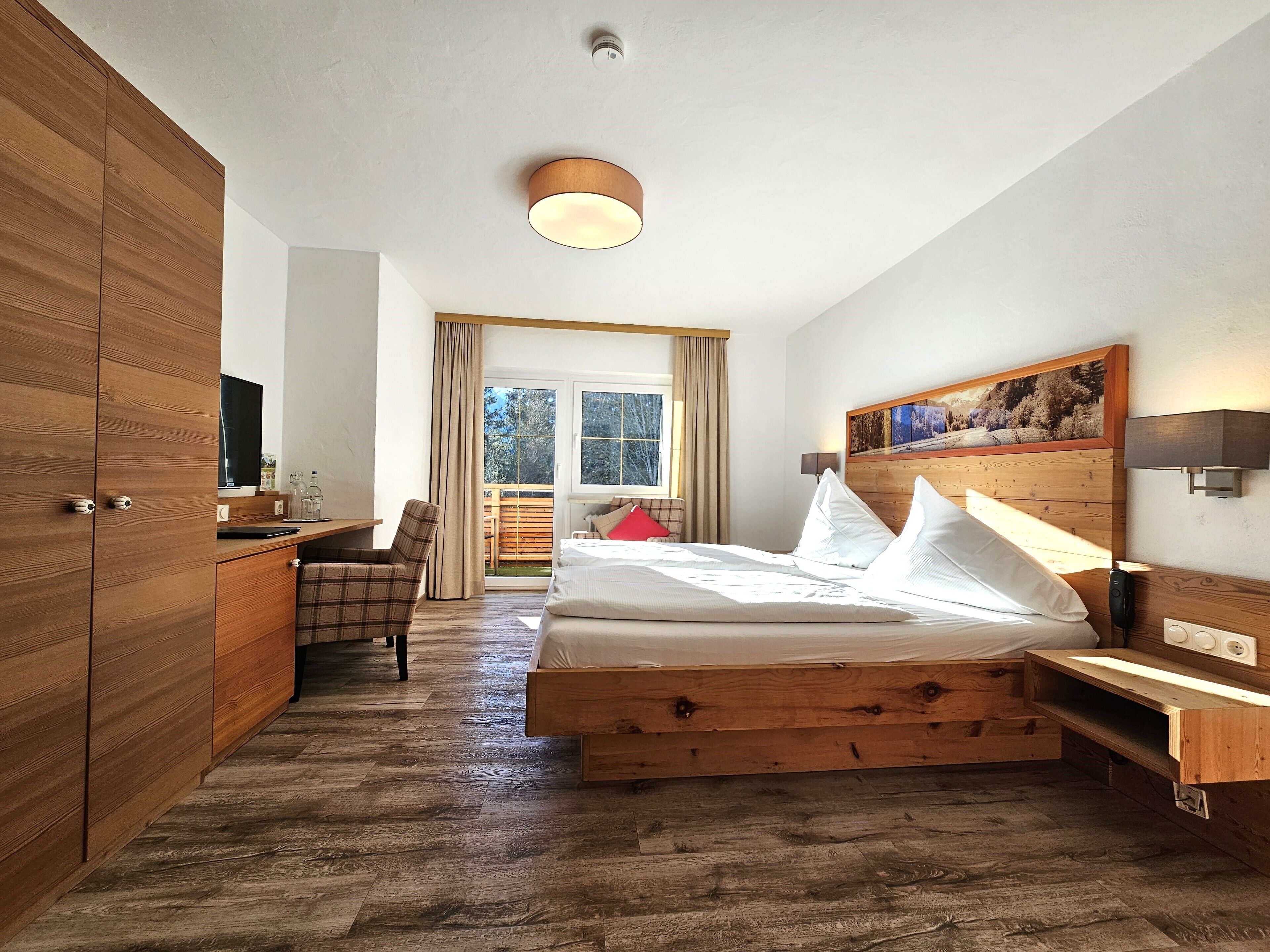 Une chambre à coucher avec un lit en bois, un bureau, une chaise et une grande fenêtre.
