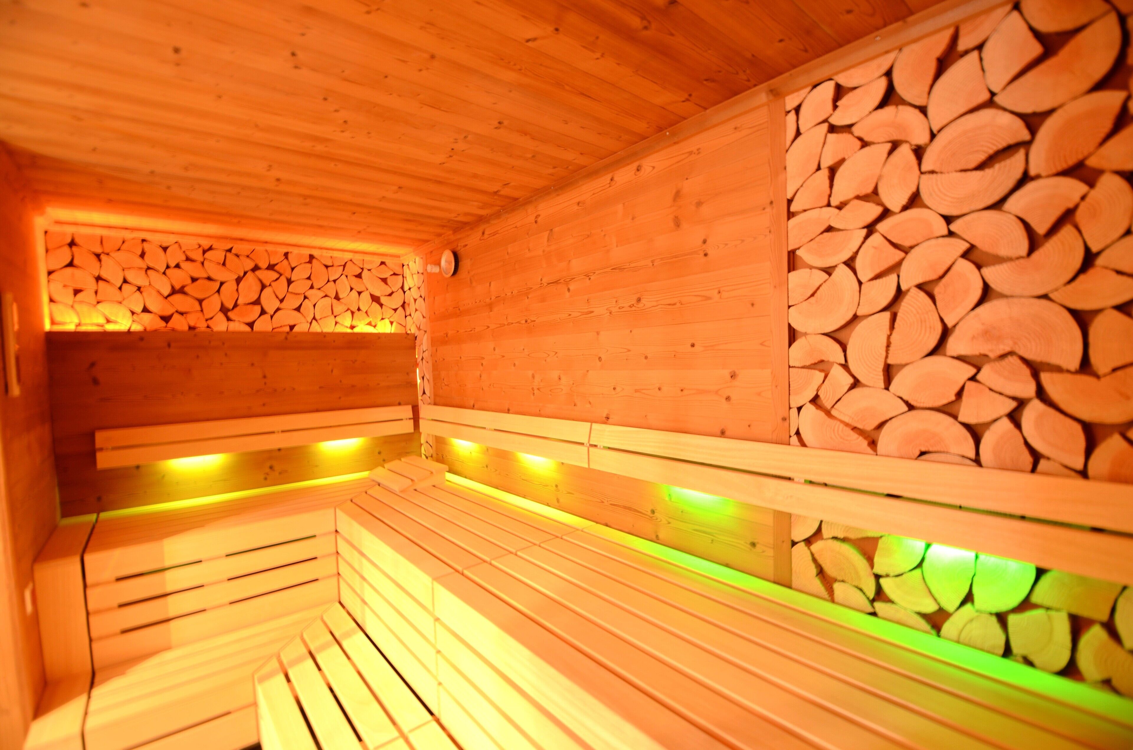 Una sauna in legno con panche e un muro di tronchi impilati.
