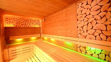 Una sauna in legno con panche e un muro di tronchi impilati.