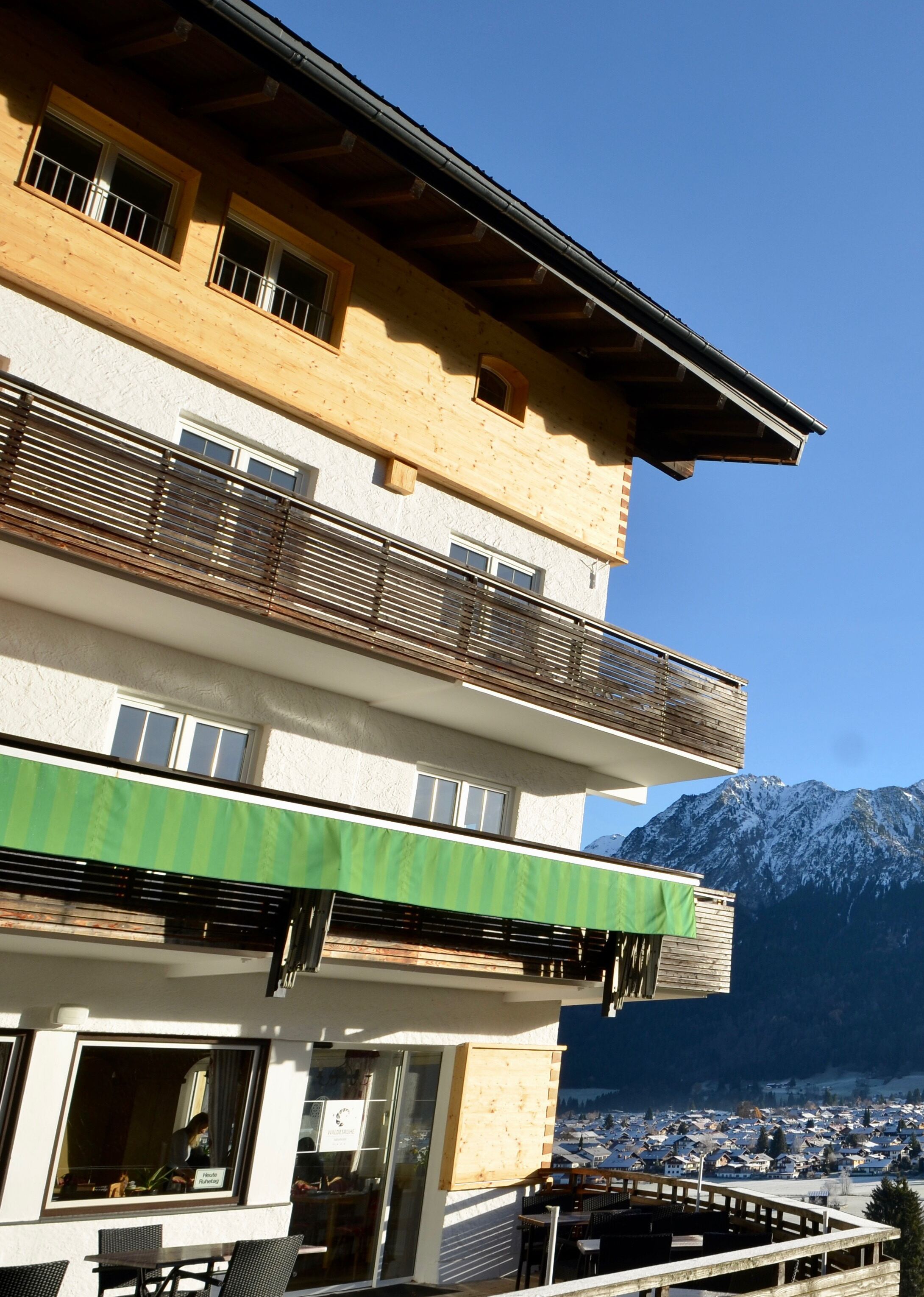 Ein mehrstöckiges Gebäude mit Balkonen, einem Restaurantbereich und Blick auf schneebedeckte Berge.