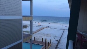A view of a beach from a balcony with a pool and a sandy area. - SUNDIAL - SITTING IN THE SAND. 3 BR, 2 BA. POOL. LESS CROWDED AREA OF BEACH. (Gulf Shores)