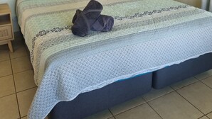 Ein ordentlich bezogenes Bett mit einer gemusterten Tagesdecke, zwei Kissen und einem gefalteten Handtuch.