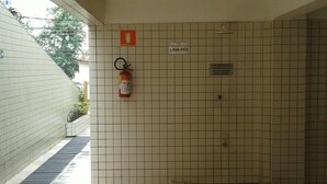 Zona doccia rivestita di piastrelle, con estintore a parete e cartello indicativo della posizione della doccia.