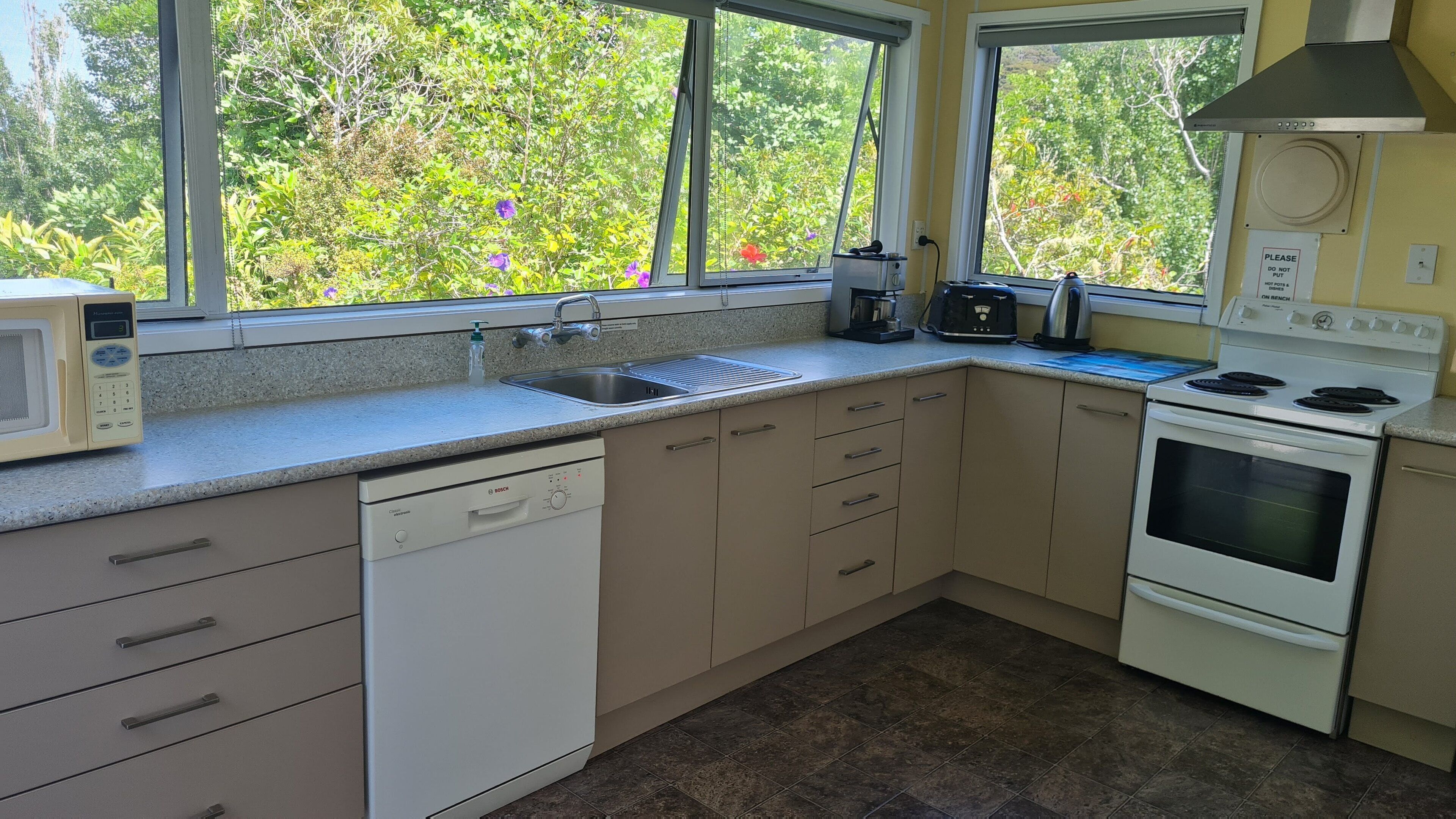 A kitchen with a Bosch dishwasher, a microwave, a sink, a stove, and a coffee maker.