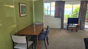A conference room with a wooden table, chairs, a television, and a window with curtains.