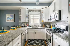 A kitchen with white cabinets, a granite countertop, a stove, and a microwave. - Pool! Out of HGTV! Linens, Bikes, Beach gear, elev, oceanview, luxury! (Wildwood Crest)
