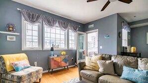 Una sala de estar con sofá, sillón, aparador y ventilador de techo.