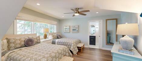 A bedroom with two beds, a ceiling fan, a door, and a window.