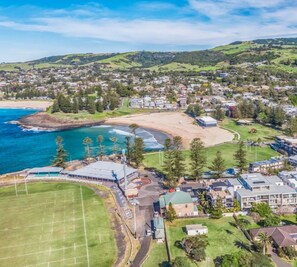 A coastal town with a large bluewater apartments complex, a beach, and a sports field.