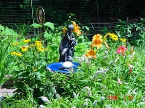 Stroll through the serene garden, surrounded by vibrant flowers and a tranquil birdbath, featuring a contemplative statue.