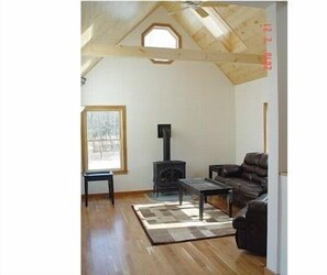 A living room with a fireplace, a sofa, and a coffee table. - Breathtaking New Premier Lake Champlain Waterfront Beach,Foliage,Ski Escape! (Addison)