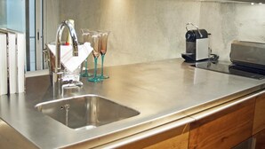 A modern kitchen with a stainless steel sink, a coffee machine, and a glass cabinet above the counter.