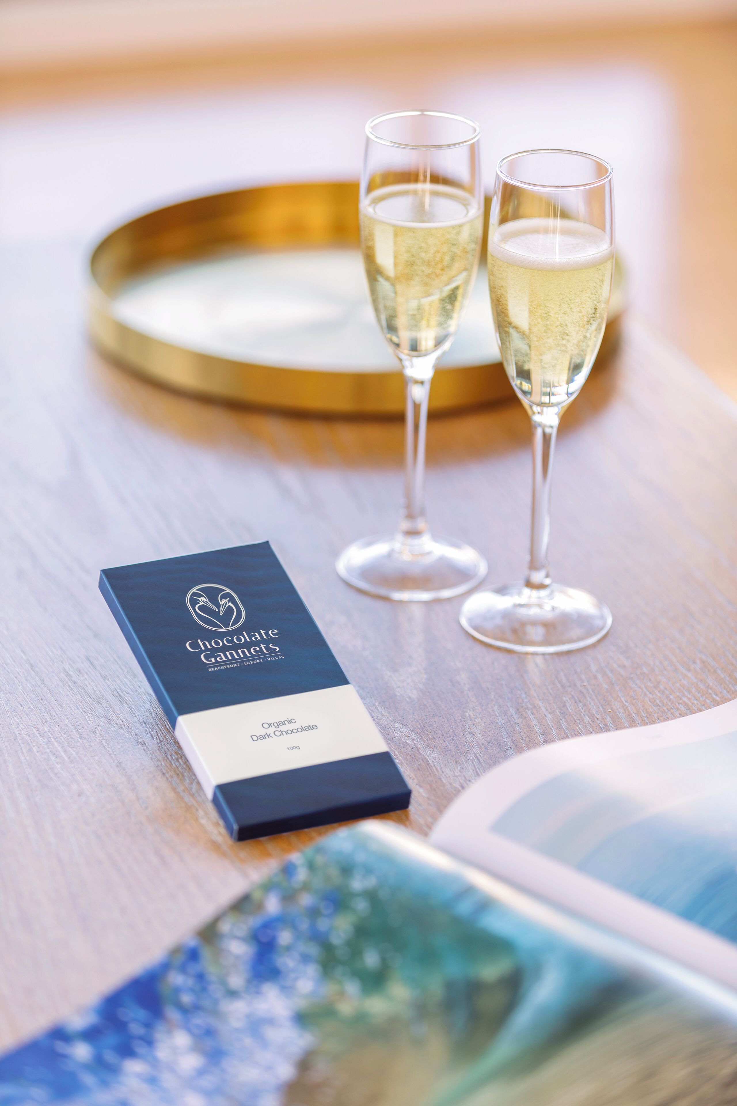 A chocolate box and two champagne glasses on a wooden table.