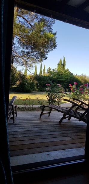 A wooden deck with two wooden chairs and a bench, overlooking a garden with various plants and flowers. - In the countryside, a very large villa to gather Family and Friends (carcasonne)