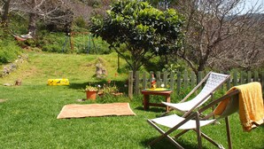 Un pati enjardinat amb un hamaca, una tanca de fusta i una cadira amb una tovallola.