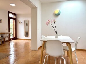 A dining area with a white table, chairs, and a vase with flowers.