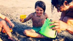Un nen jugant amb joguines a la sorra d'una platja.