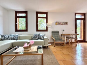 Un salon comprenant un canapé, une table basse en verre, un fauteuil, une lampe, ainsi qu’un coin repas avec une table et des chaises.