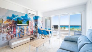 Ein modernes Wohnzimmer mit großem Fenster, Essbereich und einer farbenfrohen Wandmalerei.