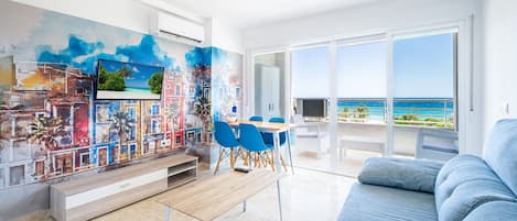Una sala de estar moderna con un amplio ventanal, un comedor y un mural colorido en la pared.