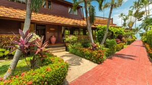 A resort with a red-tiled roof, palm trees, and a red brick pathway.
