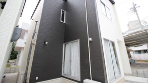 A modern building with a dark facade, large windows, and visible utility pipes. - Akizero Onnason (Onna)