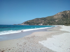 A beach with clear blue water, white sand, and a rocky hillside in the background. - Villasimius, air conditioning and pool. CIN Code IT111105C2000Q2721 (Villasimius)