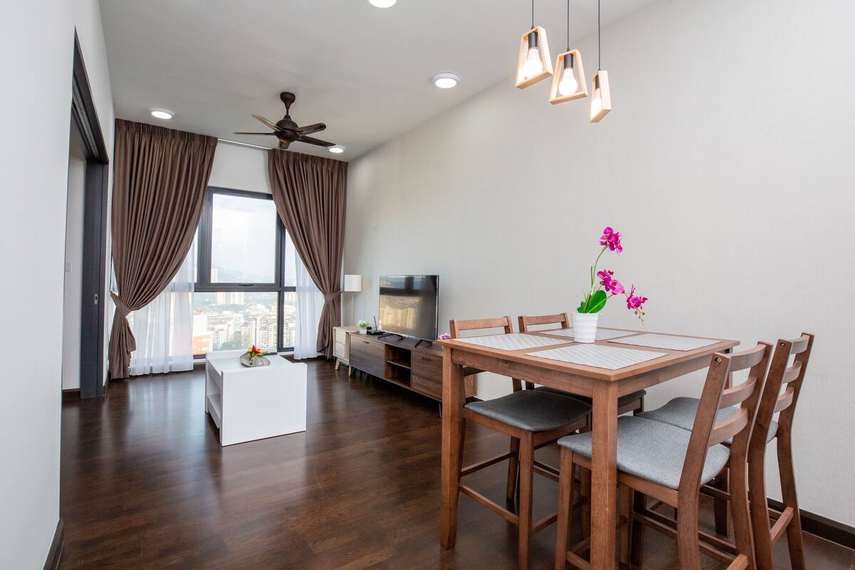 Un salon moderne comprenant une table à manger, des chaises, un téléviseur et un ventilateur de plafond.
