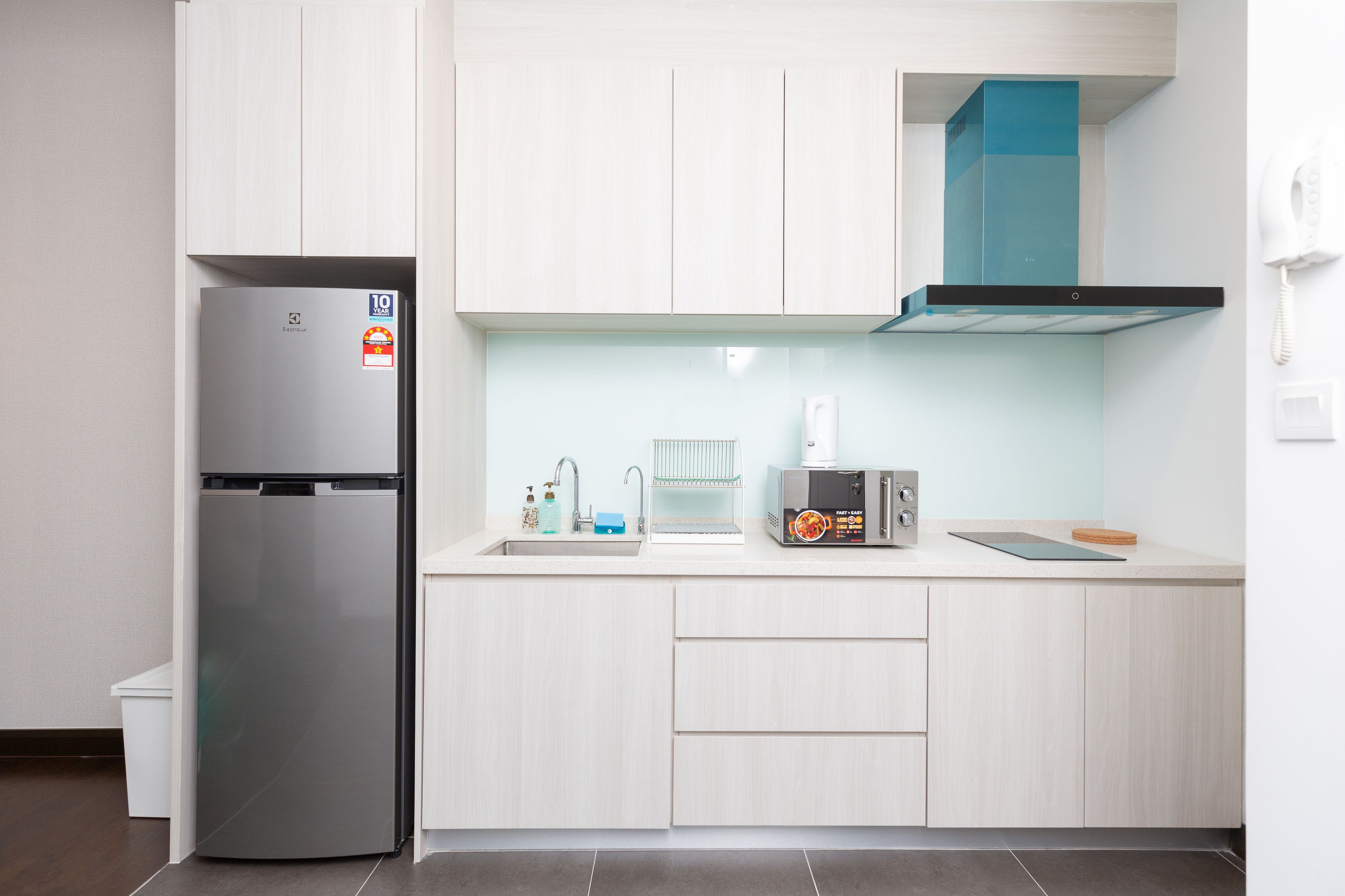 A modern kitchen with a stainless steel refrigerator, a built-in oven, a microwave, and a coffee maker.