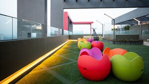 A rooftop terrace with colorful, modern seating and a view of the cityscape.