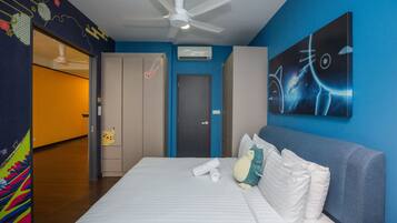 Una habitación de hotel con una cama, un ventilador de techo, una puerta y una pared con un cuadro.