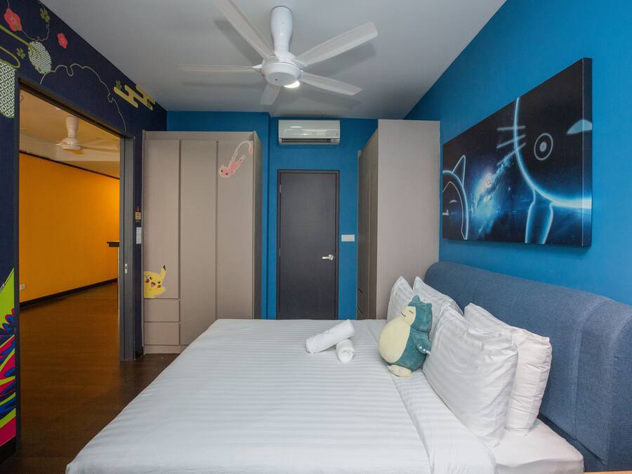 Una habitación de hotel con una cama, un ventilador de techo, una puerta y una pared con un cuadro.