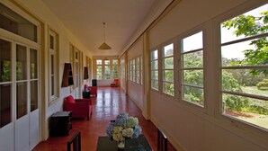 A corridor with a dining table and chairs, a red sofa, and a vase of flowers.