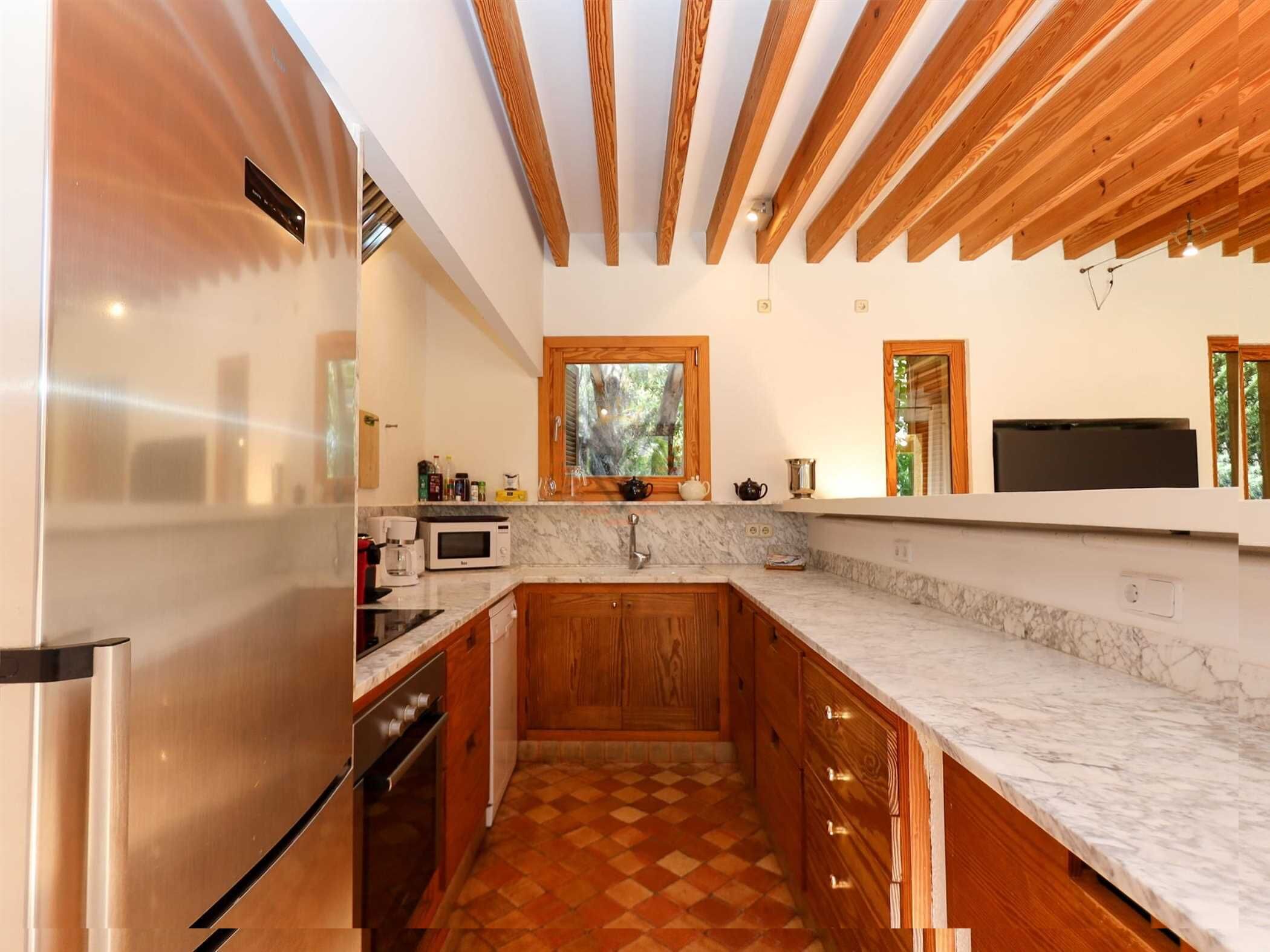 Una cuina moderna amb armaris de fusta, taulell de marbre i forn integrat.