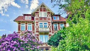 Een groot, twee verdiepingen tellend huis met een symmetrische gevel, meerdere ramen en een balkon.