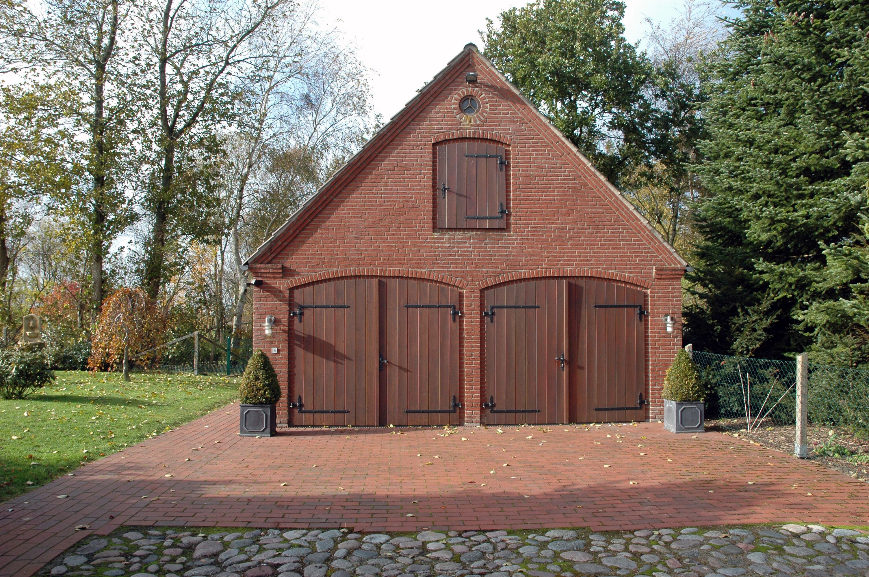 Un edificio de ladrillo con techo triangular y dos grandes puertas de madera.