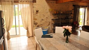 Un comedor con una mesa preparada para dos, un jarrón de flores y una pared de piedra al fondo.