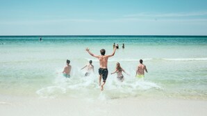 Escena de playa con gente jugando en el agua.