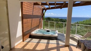 A hot tub in a covered outdoor area with a view of the ocean.
