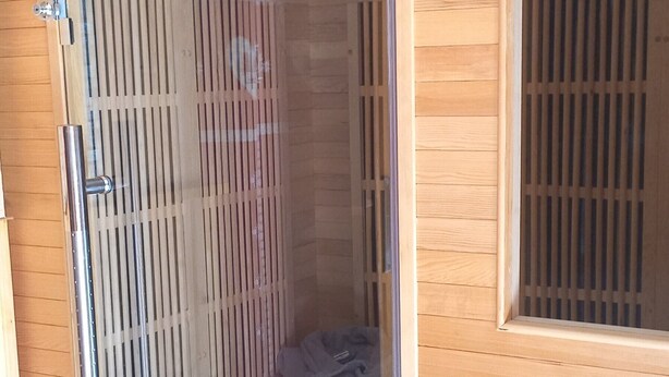 Une pièce dotée d’une porte coulissante donnant sur une salle de bain, d’un mur en bois et d’une fenêtre avec des stores.