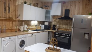 Une cuisine avec des murs en bois, un réfrigérateur en acier inoxydable, un four à micro-ondes, une cuisinière et un lave-linge.