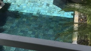 A clear swimming pool with a tiled deck, surrounded by palm trees and a covered seating area. - Beautiful new bungalow with views. (Le vauclin)