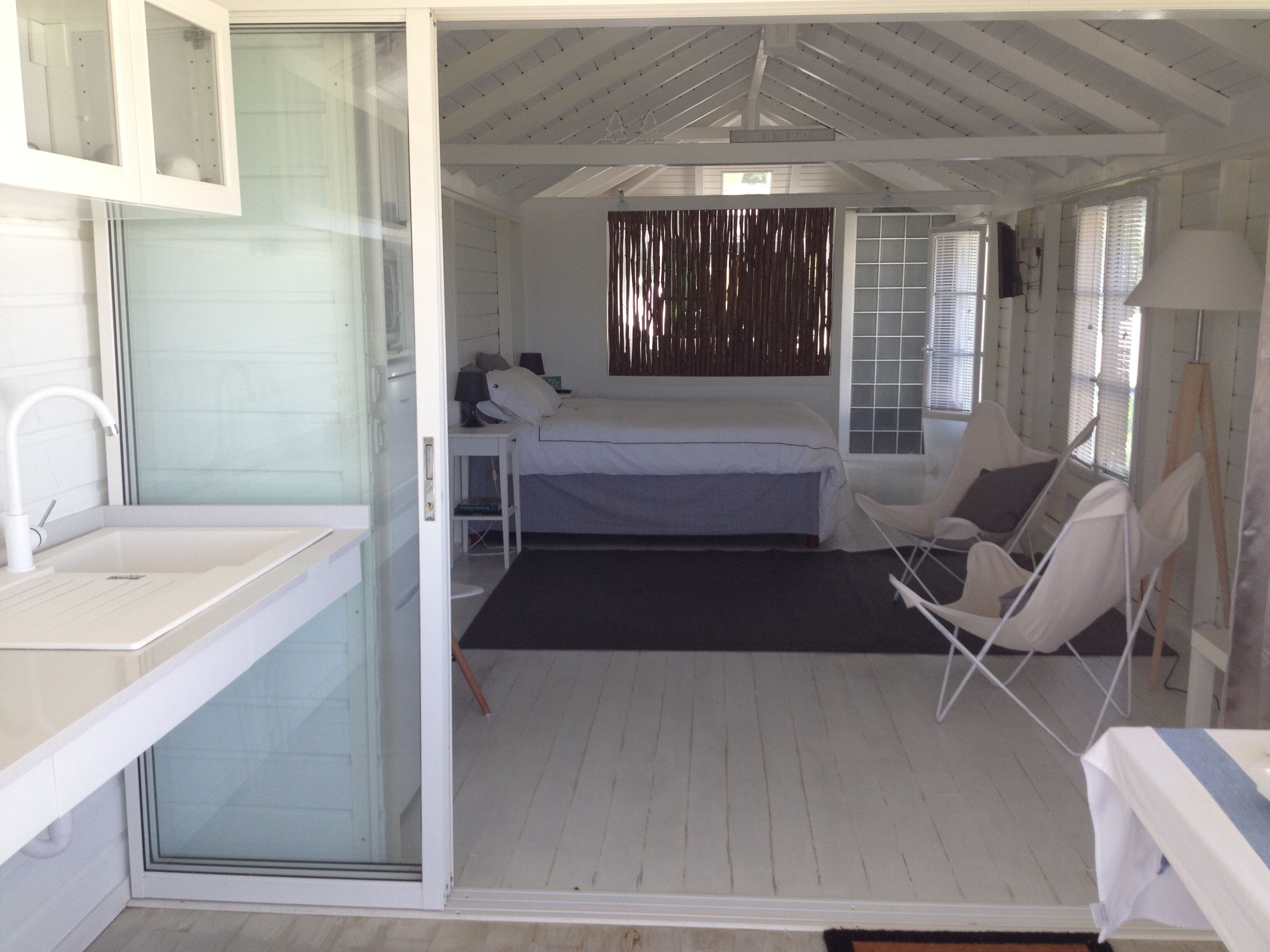 Ein Zimmer mit Bett, Stuhl, kleinem Tisch und Waschbecken.