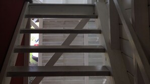 A staircase with a handrail leading to a landing with a wall-mounted sign listing amenities like 'The Beach' and 'Tropical Juices'. - Beautiful new bungalow with views. (Le vauclin)