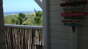 A view from a balcony with a signboard listing amenities like 'The Bar', 'Happy Hours', and 'Tropical Garden'. - Beautiful new bungalow with views. (Le vauclin)
