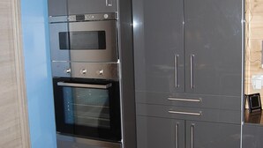 Une cuisine moderne dotée d’appareils électroménagers intégrés, notamment un four à micro-ondes, un four et un réfrigérateur.