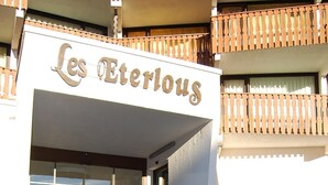L’entrée d’un immeuble, avec une enseigne indiquant « Les Eterlous », et un escalier menant à cette entrée.