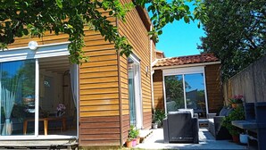 Een houten huis met een terras, grote schuifdeuren en tuinmeubilair.